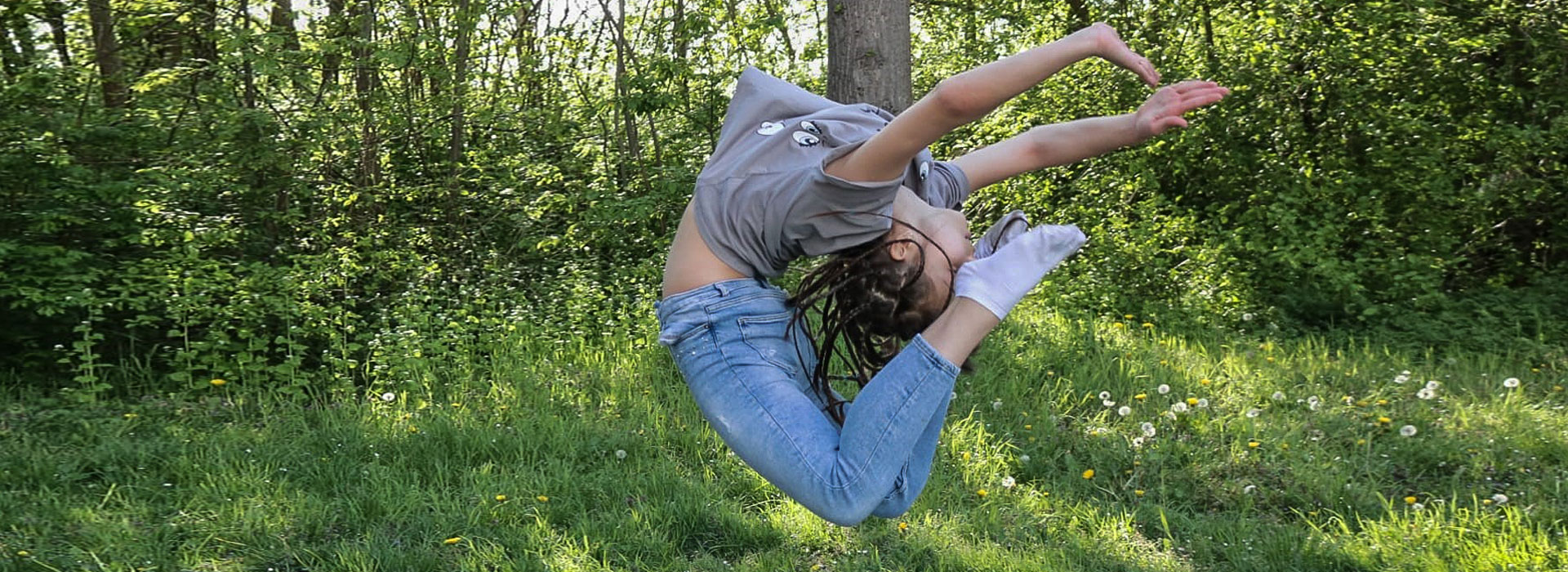 Rhythmische Sportgymnastin während eines Sprungs in der Natur.